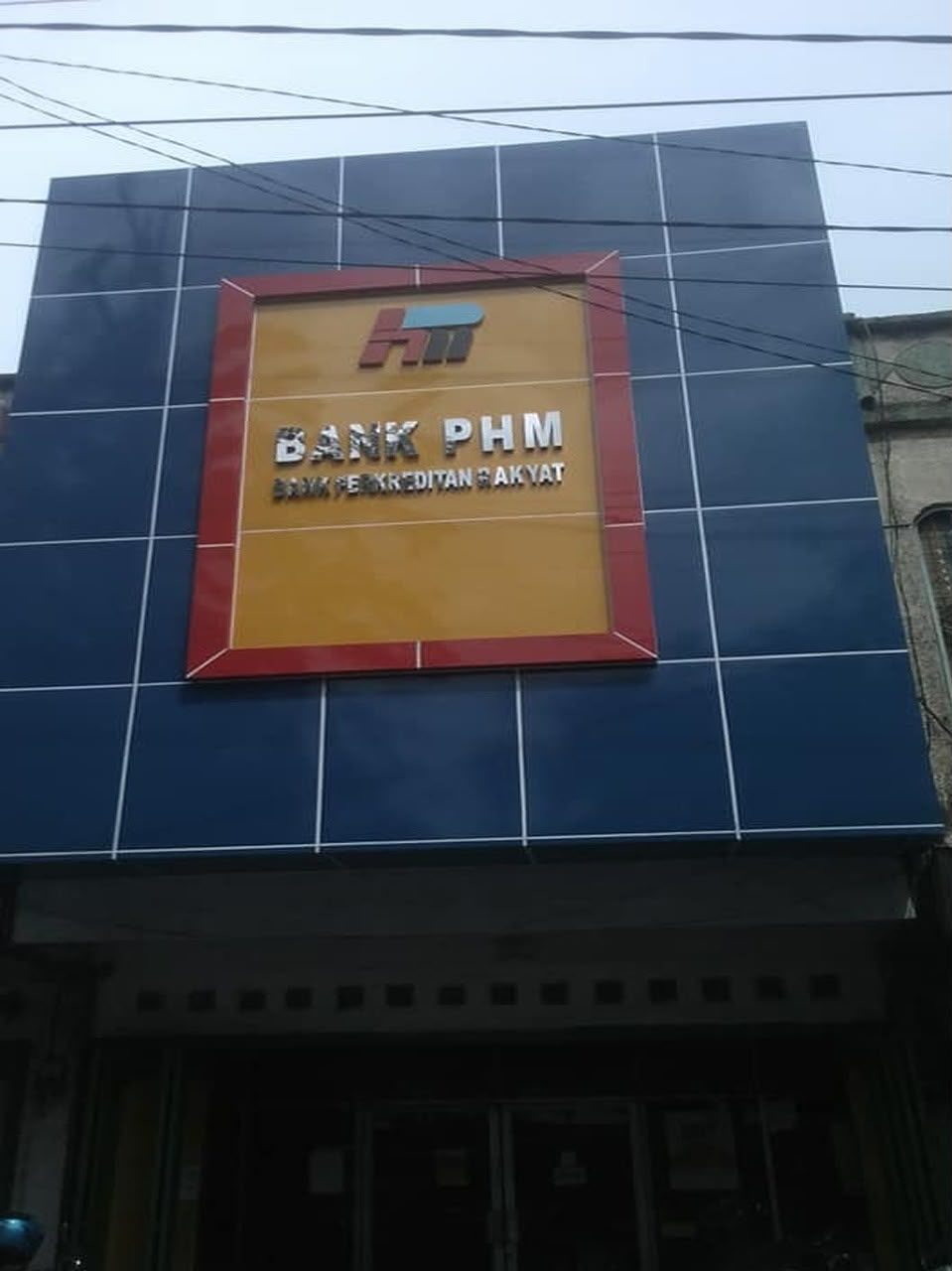 Fasad bangunan dengan panel ACP biru dan bidang identitas